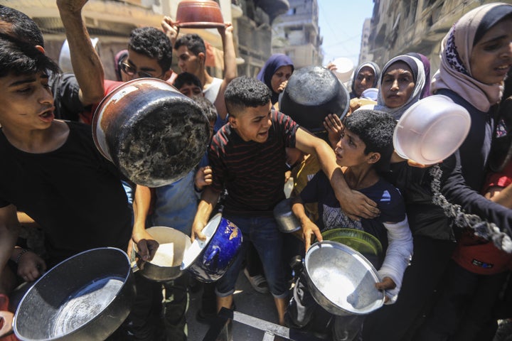 Palestinians receive food aid as people continue to struggle with hunger as a result of ongoing Israeli attacks in Gaza City on June 18, 2025.